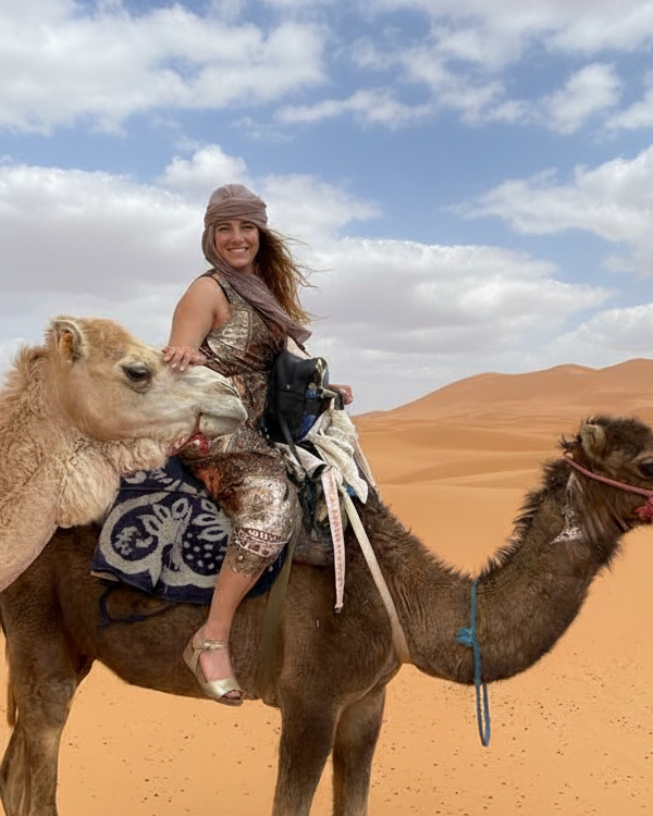 Woman on a camel, petting another camel
