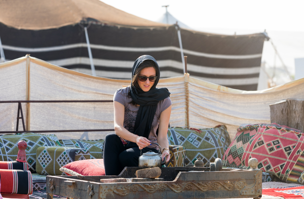 donna con capo coperto che versa te in un accampamento